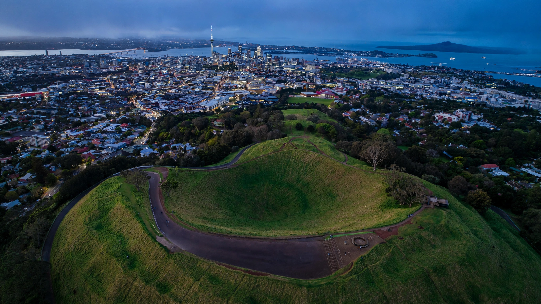 Auckland skyline from Mount Eden over the volcanic crater and harbour at dusk